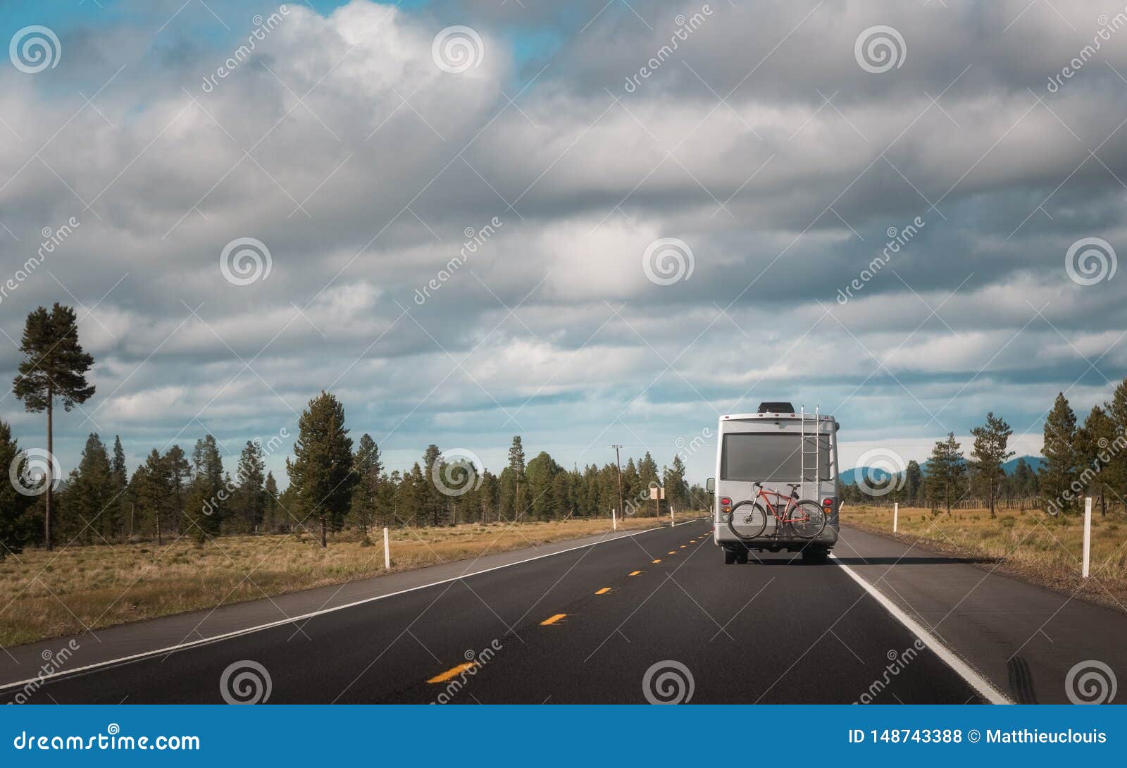 recreational vehicle with bike hanging on the rear driving through the countryside. travel and wanderlust concept image with copy