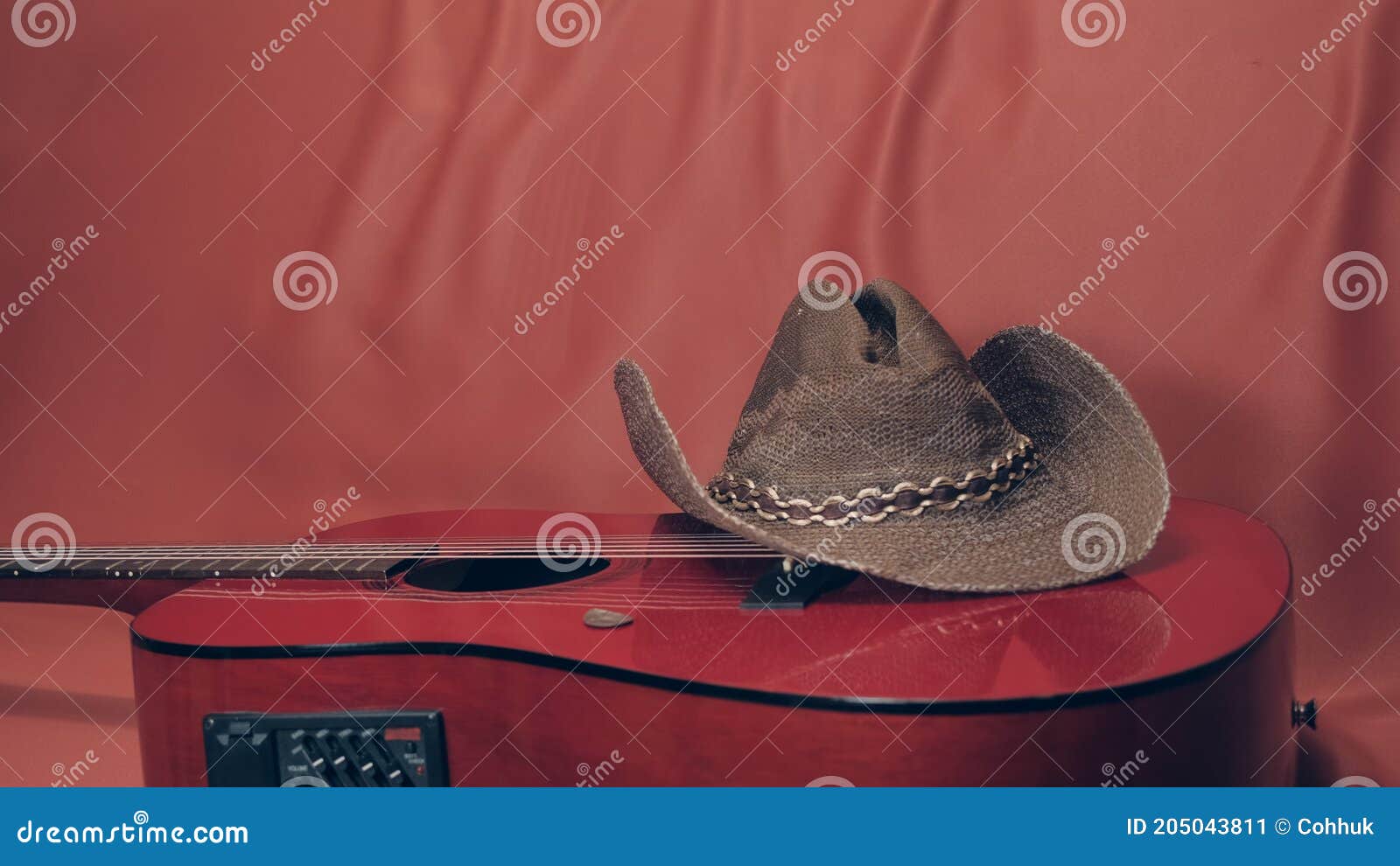 red acoustic guitar with a cowboy hat on it
