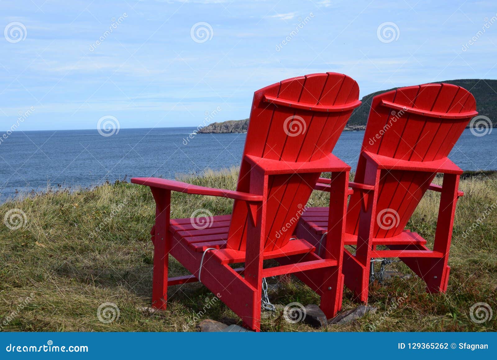 Red Adirondack Chairs On The Edge Of A Cliff Overlooking The Ocean