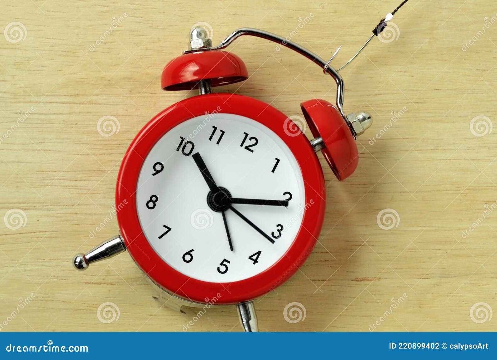 Red Alarm Clock with Fishing Hook - Concept of Stealing Time Stock