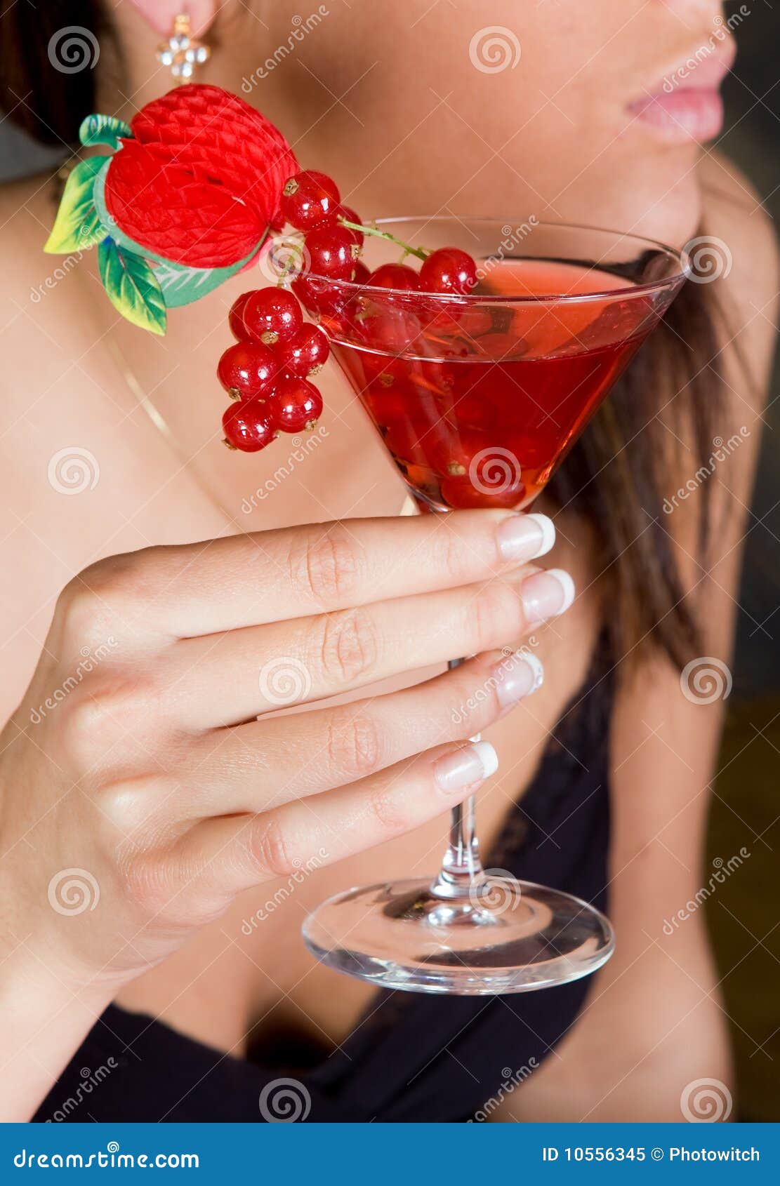 Red berries in a cocktail. Young woman holding a cocktail with red berries