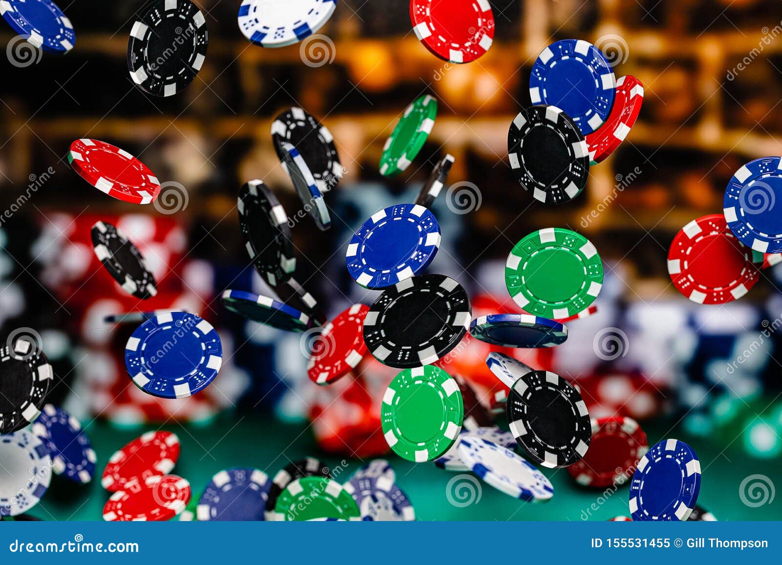 Red, Blue, Black and Green Clay Poker Chips Cascading in Front of a Background of Stacked Poker