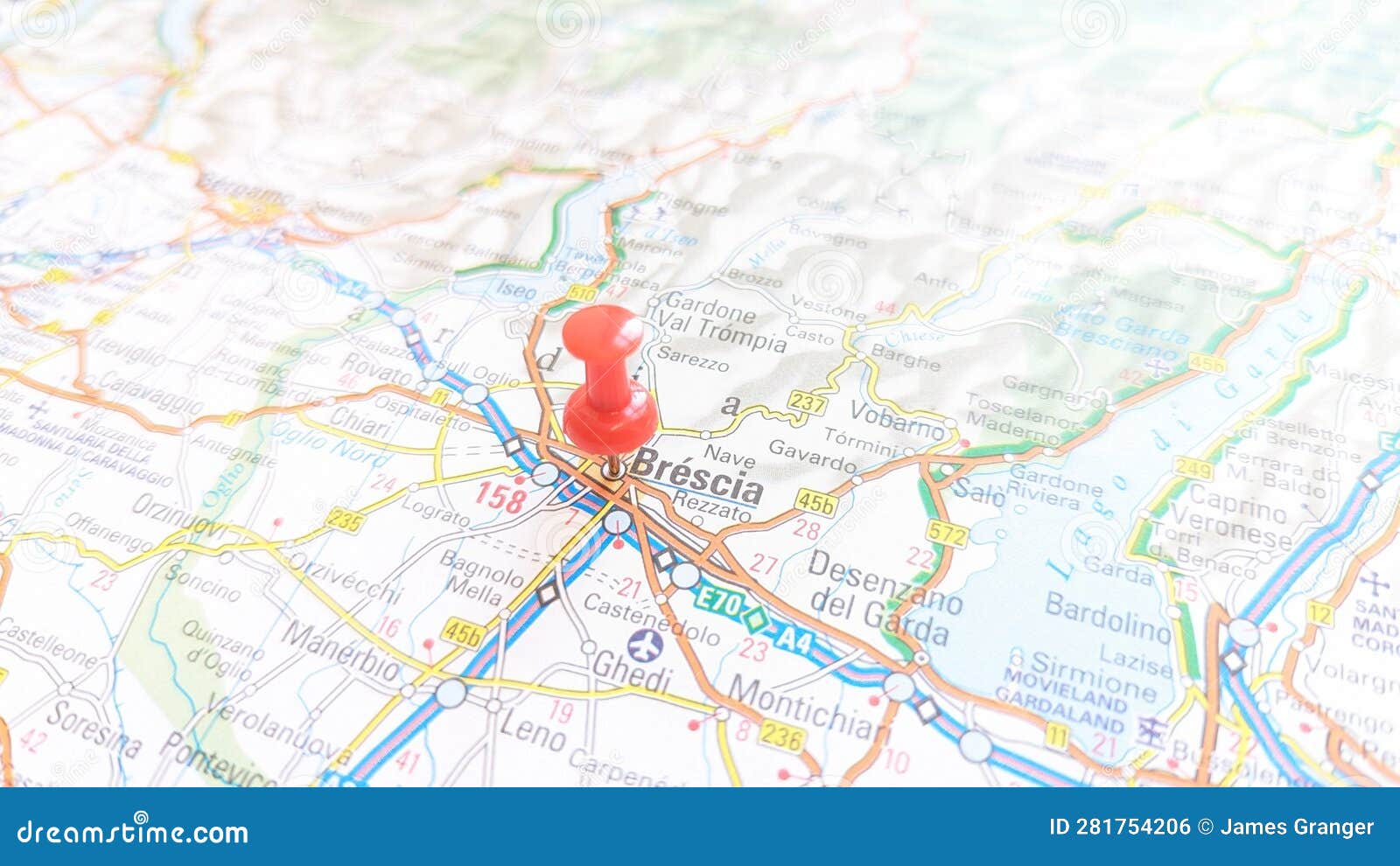 a red board pin stuck in brescia on a map of italy