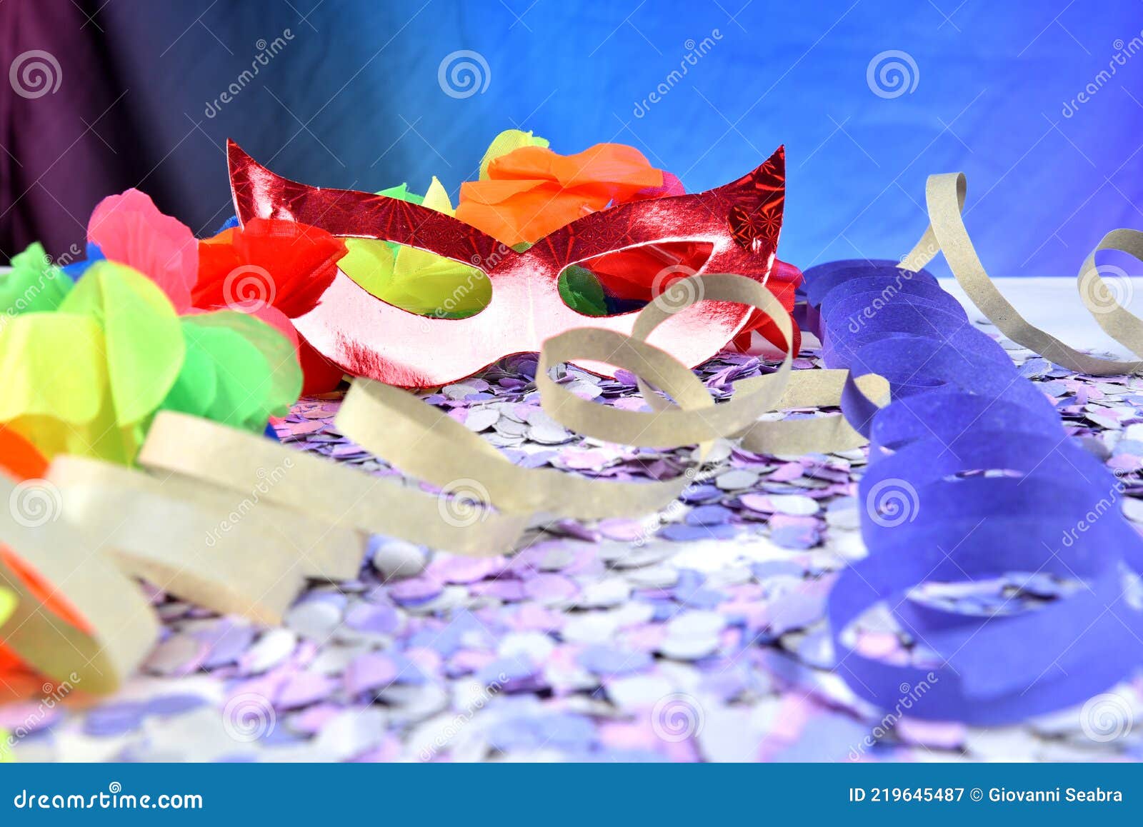 red brazilian carnival party costume mask on colorful confetti background with space for text