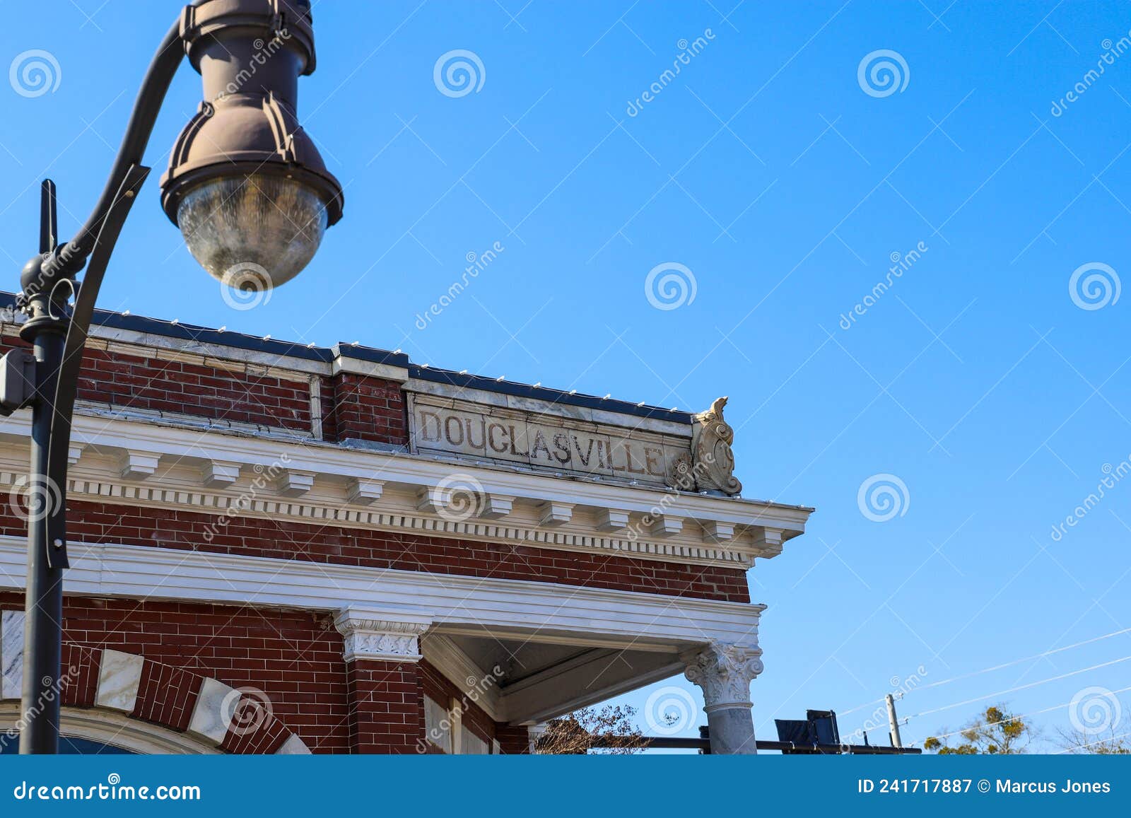 a red brick building with white marble trim with the word douglasville on the top with a tall black curved light post