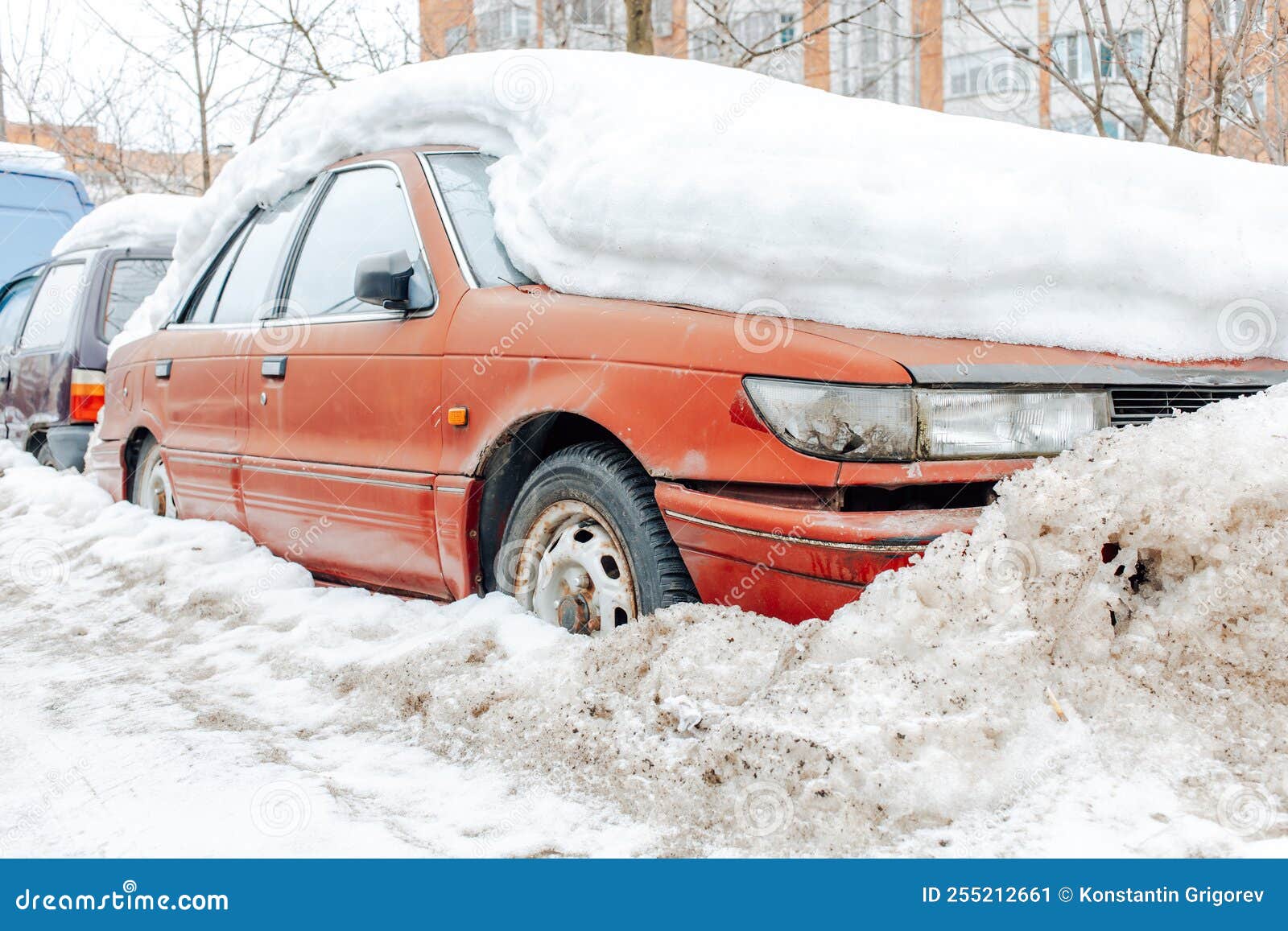 Red Car Parked in Snowdrift. Old Rusty Auto Covered in Snow. Wheel