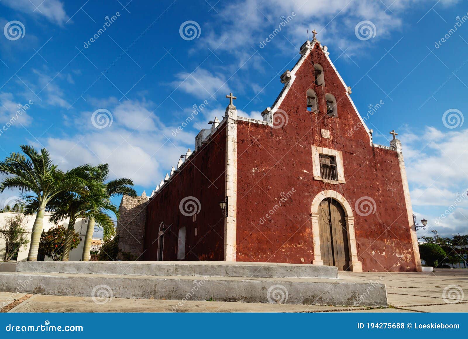 red colonial church itzimna in a park with palm trees, merida, yucatan, mexico
