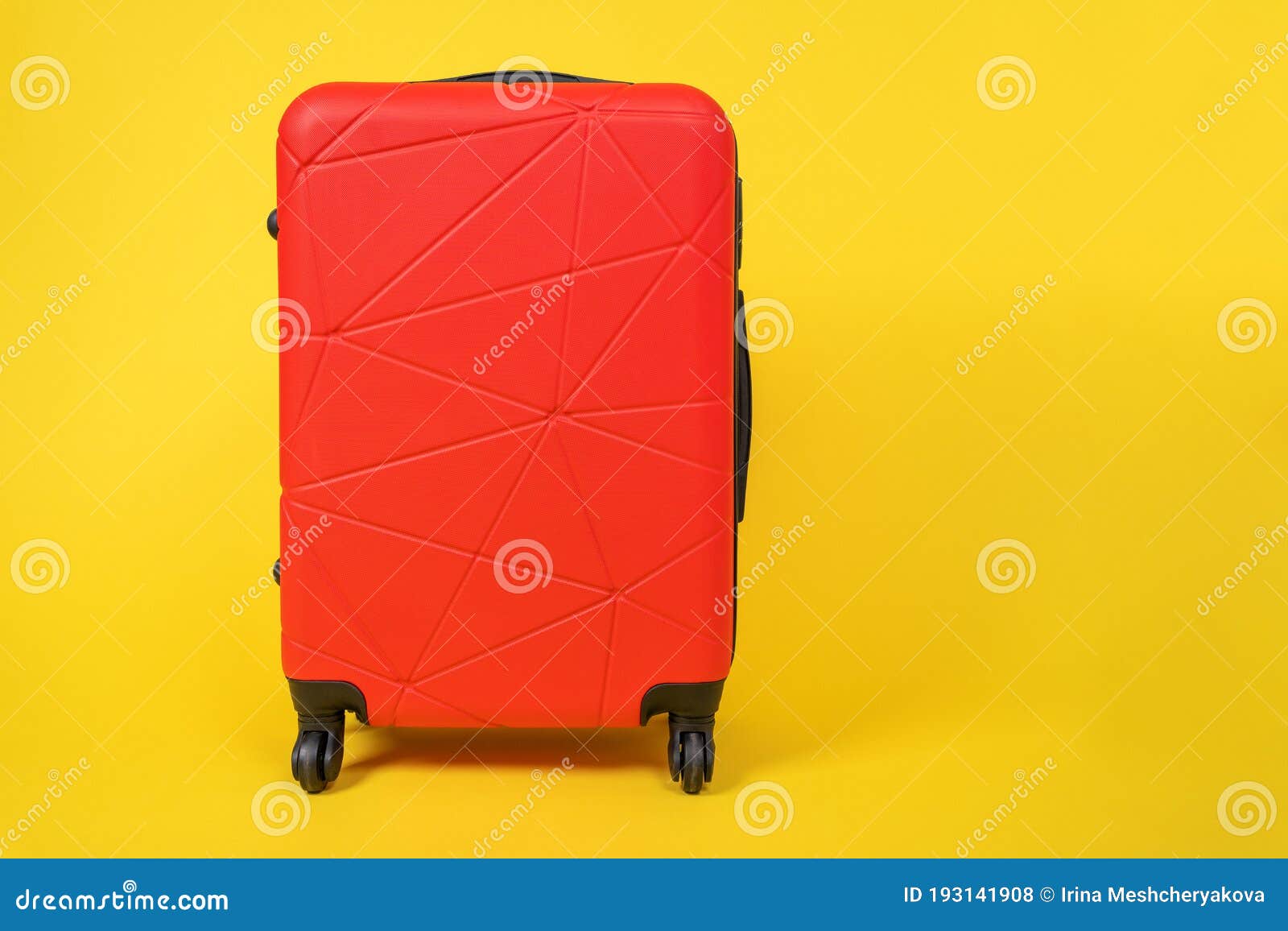 red comfortable roomy suitcase on wheels with handle for travel stands on yellow background, front view, copy space for