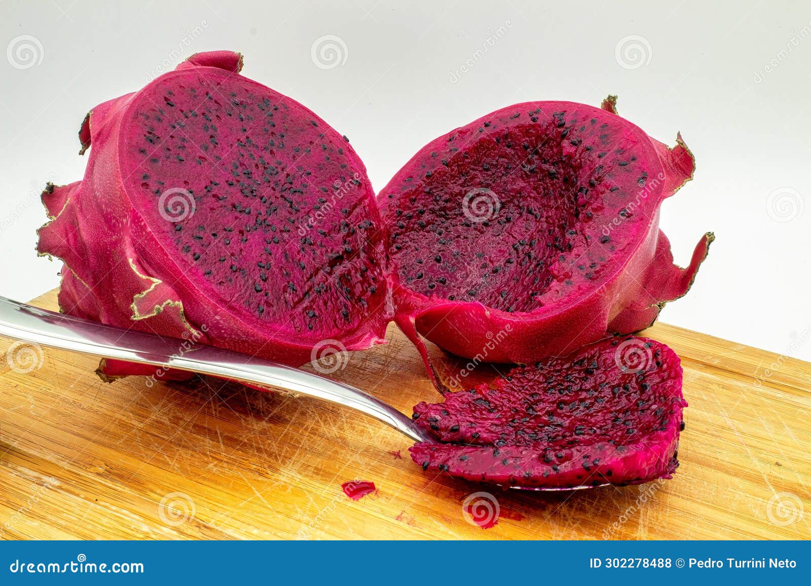 red dragon fruit, aka pitaia or pitaya. red pitaya cut in half and with a portion of the pulp in a spoon.