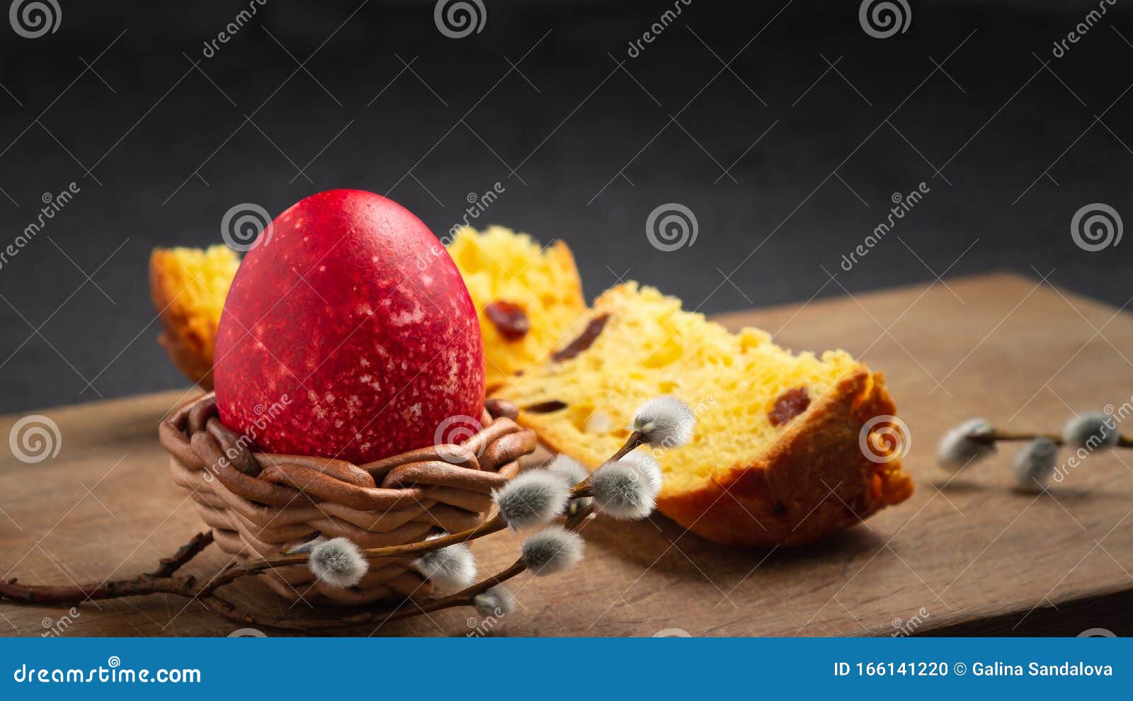 red easter egg in wisker stand and slice of easter cake on a cutting board on a dark table - traditional easter