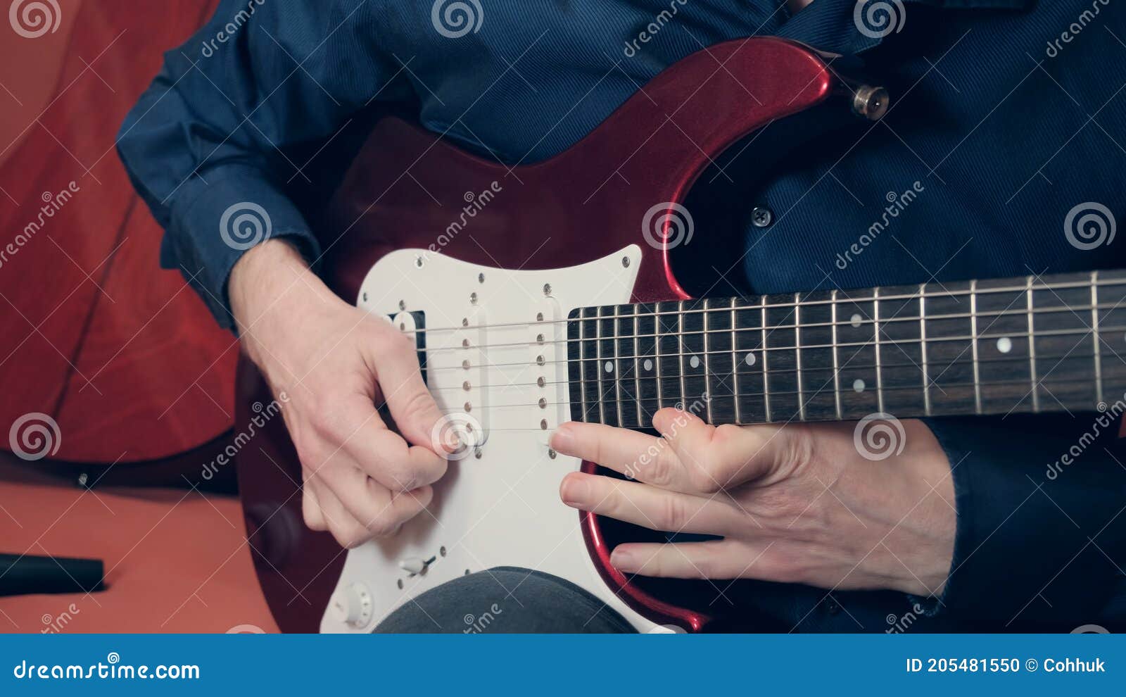 man plays the bottom string of an electric guitar