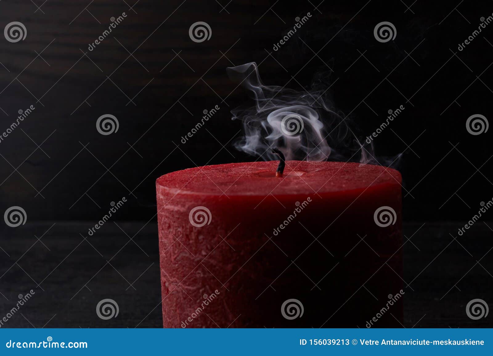 Red Extinguished Candle with Smoke Trailing Off the Wick on Black