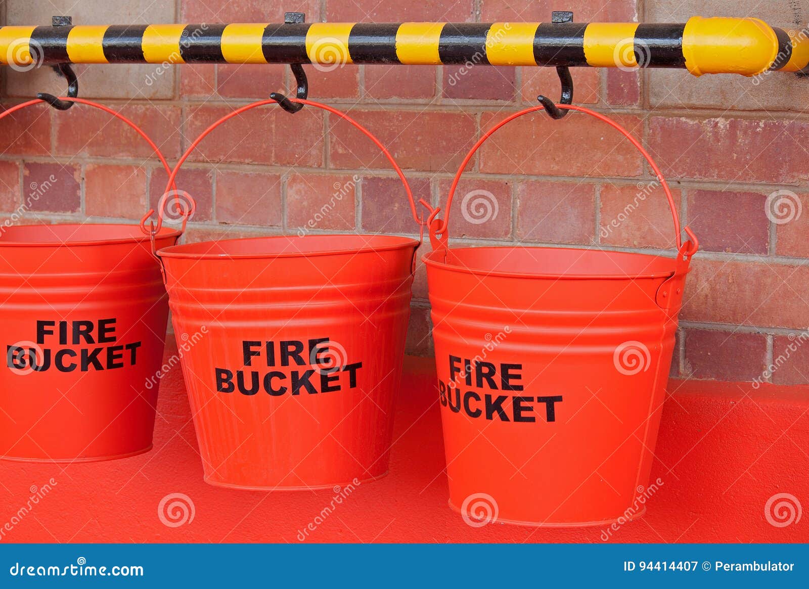 RED FIRE BUCKETS IN A ROW. Red and white painted fire buckets.