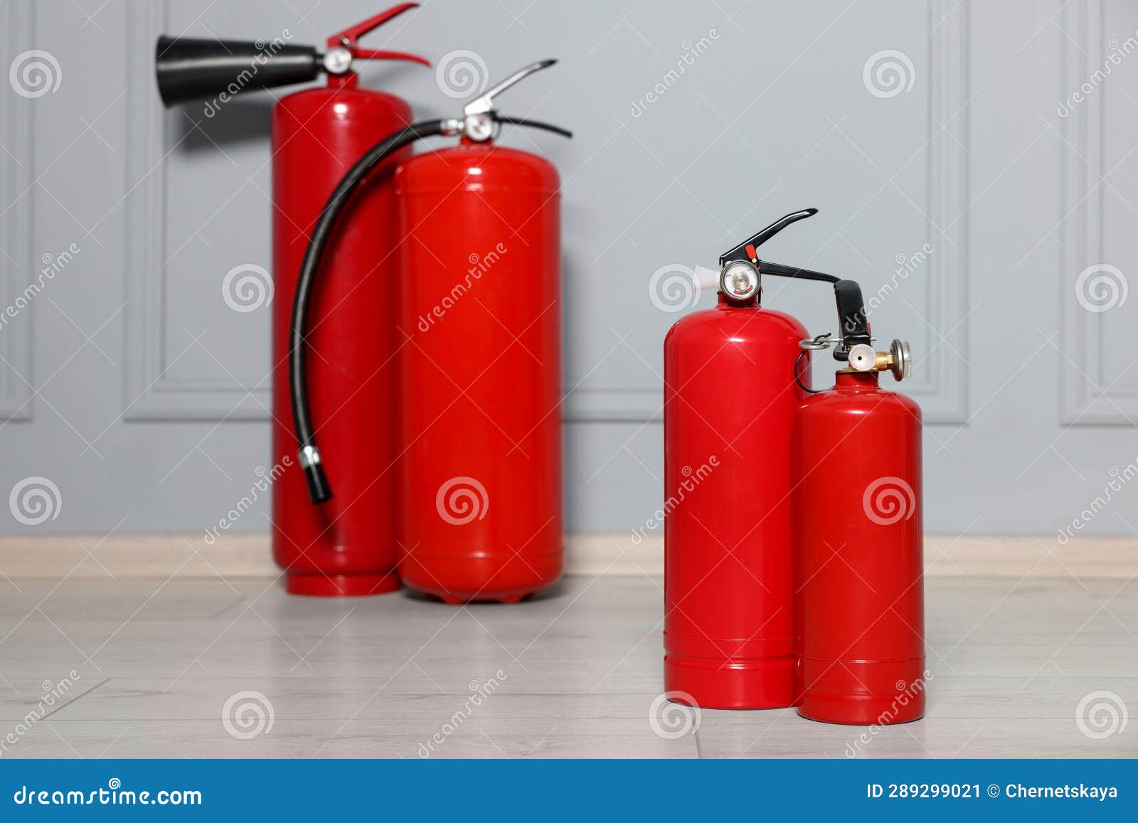 Red Fire Extinguishers Near Grey Wall, Selective Focus Stock Image