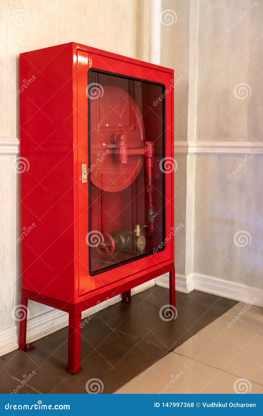 Red Fire Hose Cabinet On Brown Tile Floor Against White Wall Stock