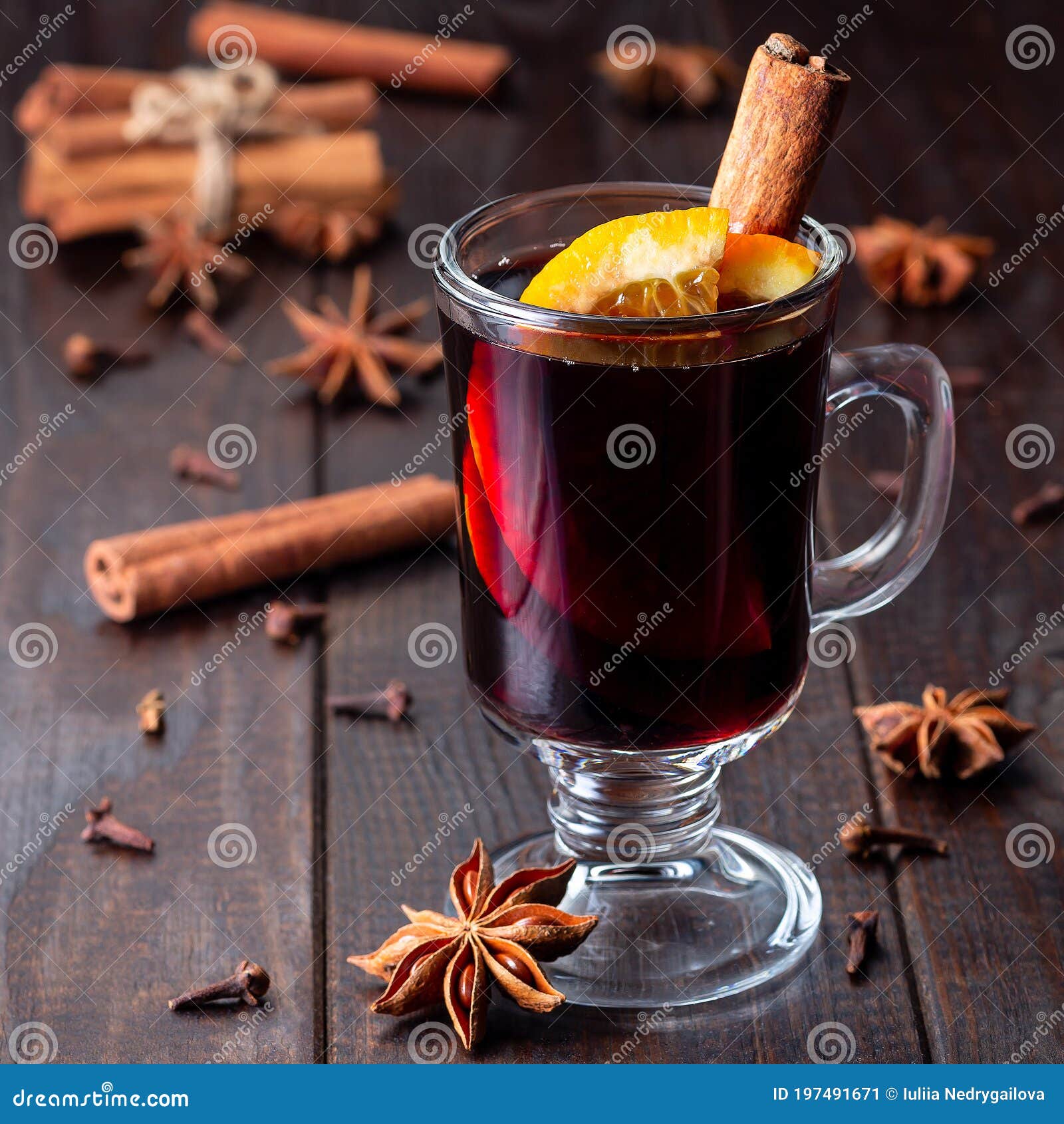 red glogg or mulled wine with orange slices and cinnamon stick on dark wooden background, square format
