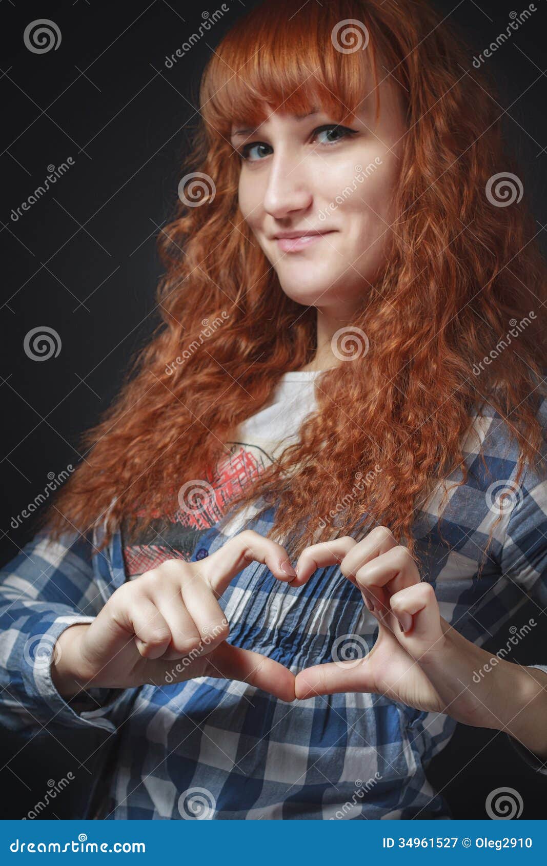 Portrait of a beautiful girl with red hair that shows fingers heartred-haired girl shows heart