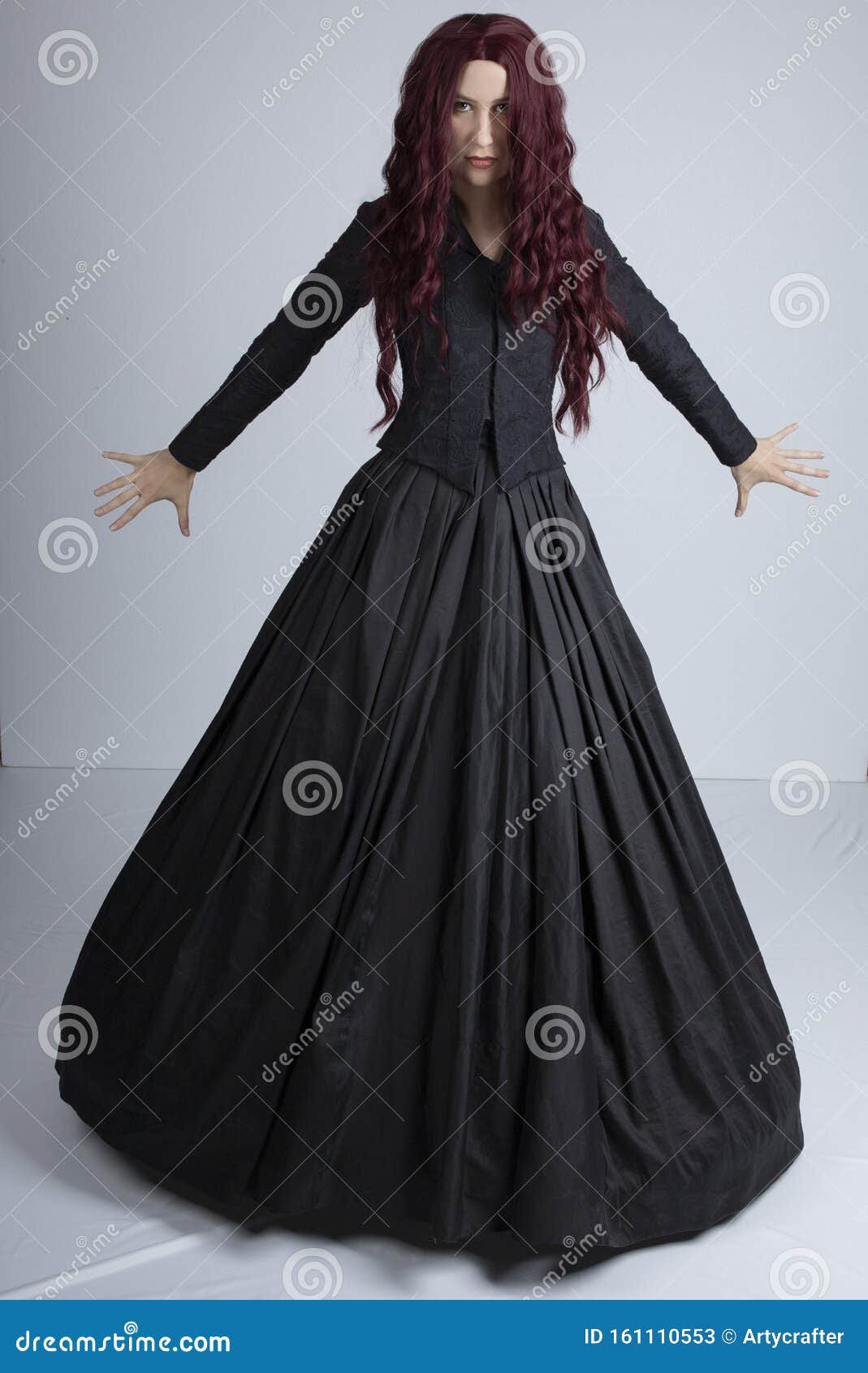 red-haired woman in black victorian ensemble and a witch-like pose