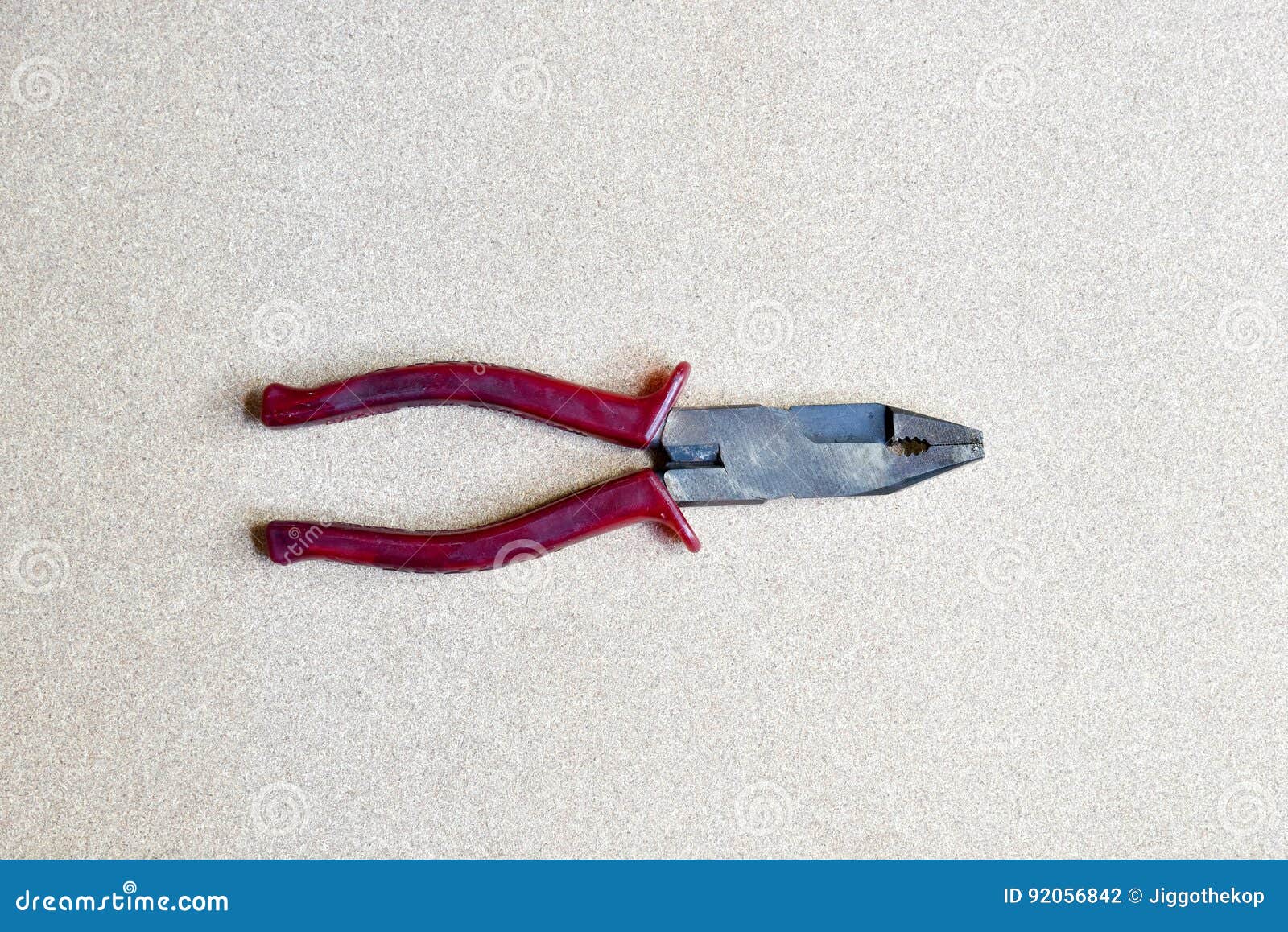 red handled pliers on wood background