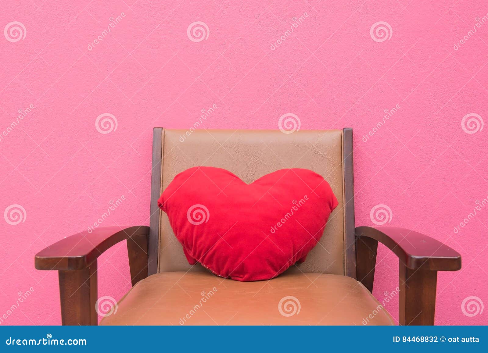 Red Heart Pillow on the Chair Wall Pink Background . Stock Photo