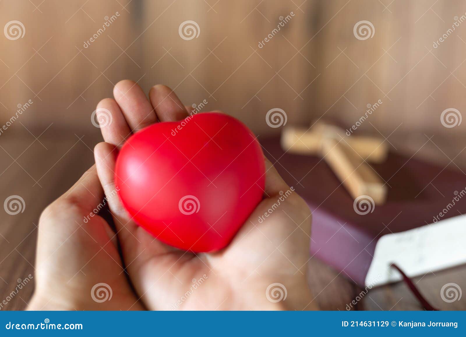 a red heart  on hand and a cross on the scriptures. a blessing from god with the power and power of holiness, which brings