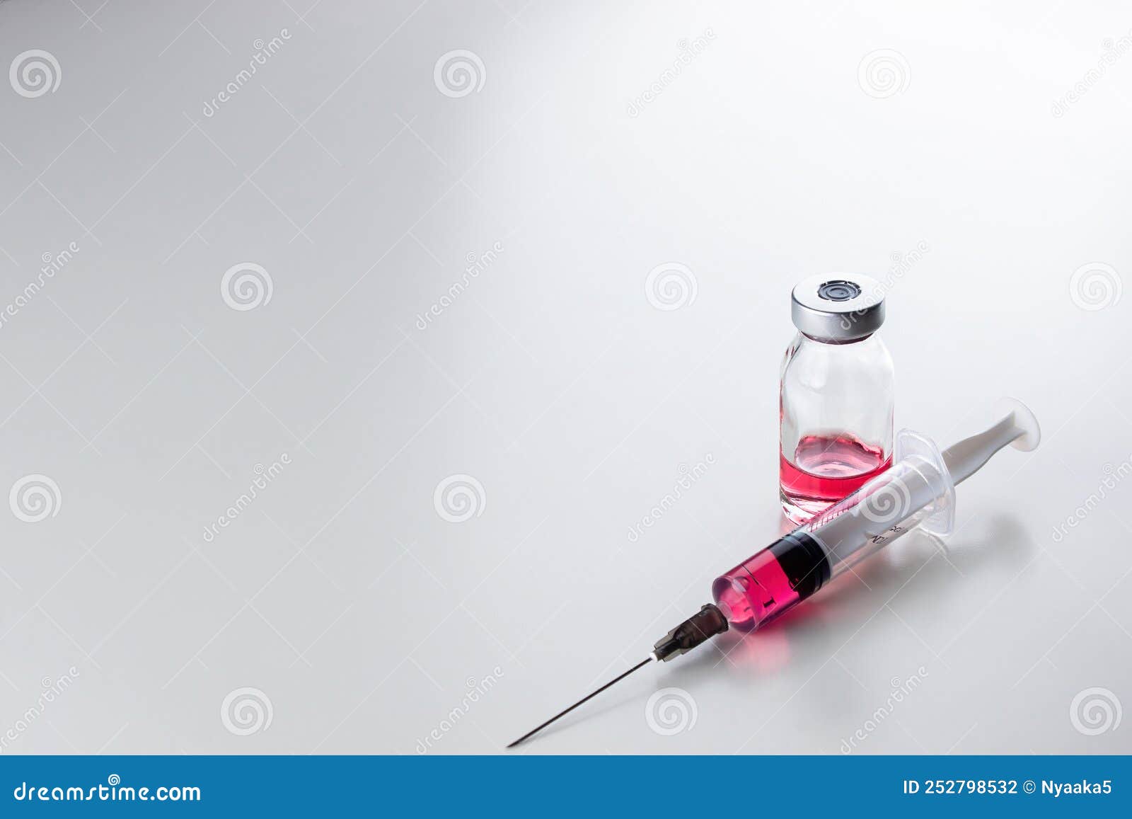 red liquid vitamin b12 in a disposable syringe with a needle and in a glass ampoule on a white background.