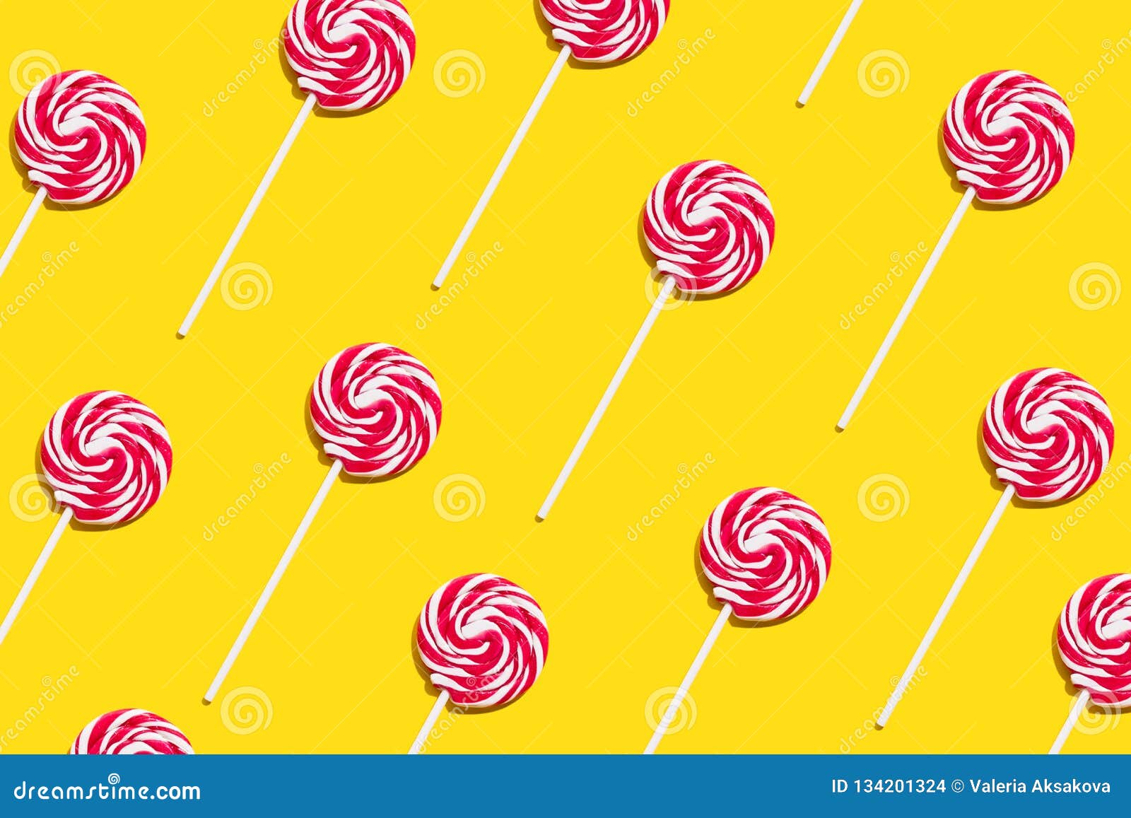 Colorful funny appetizing lollypop swirl candy on stick on yellow backgroun...