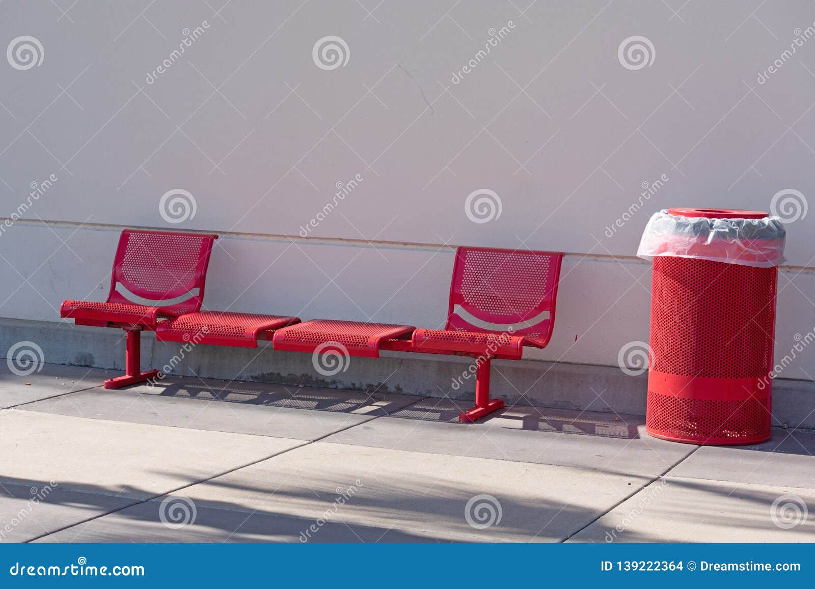 Red Metal Bench Set And Garbage Can Outside A Building Stock Photo