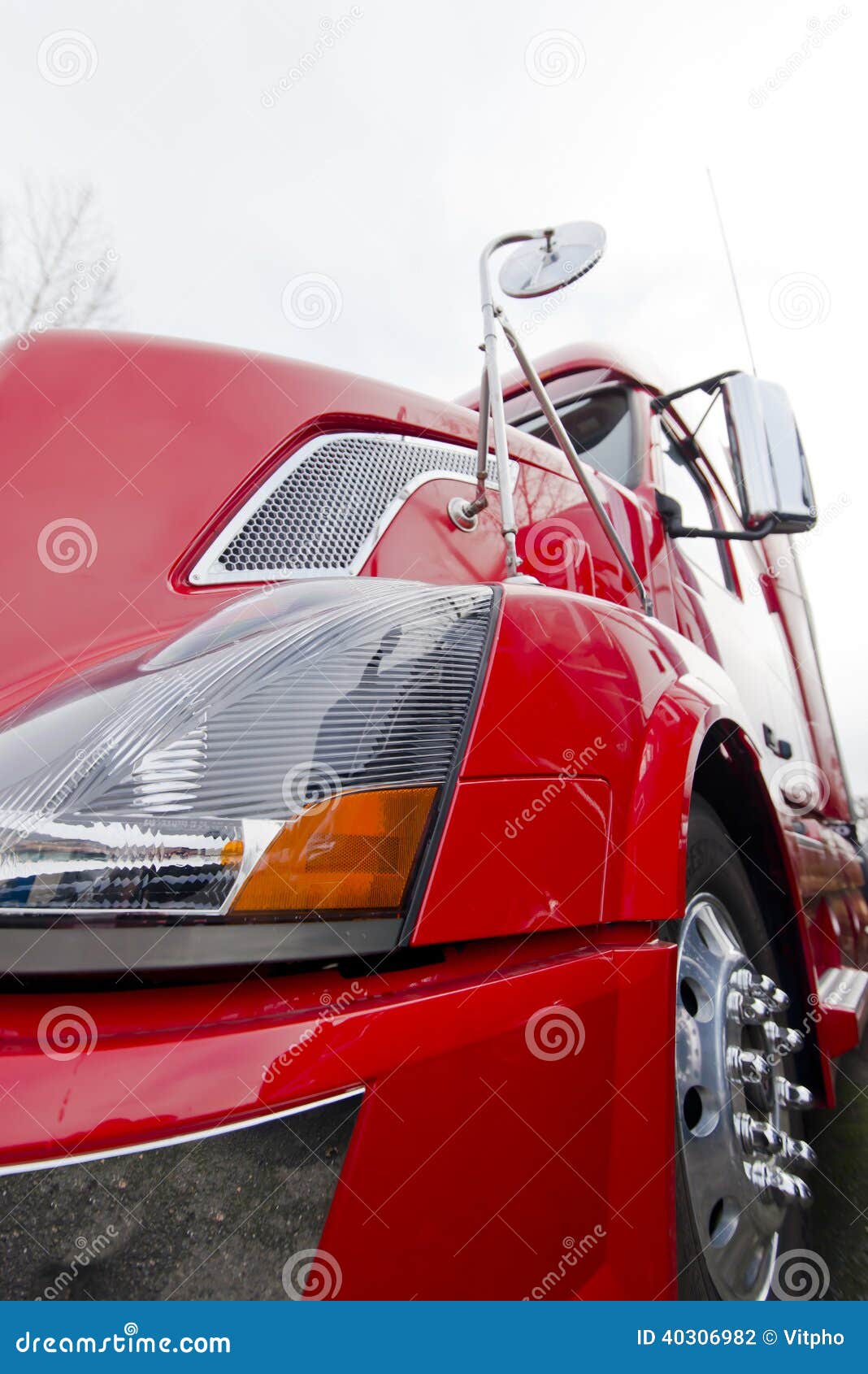 Bamper,wheel,mirror, headlight, body of bright red modern semi truck close view on light background