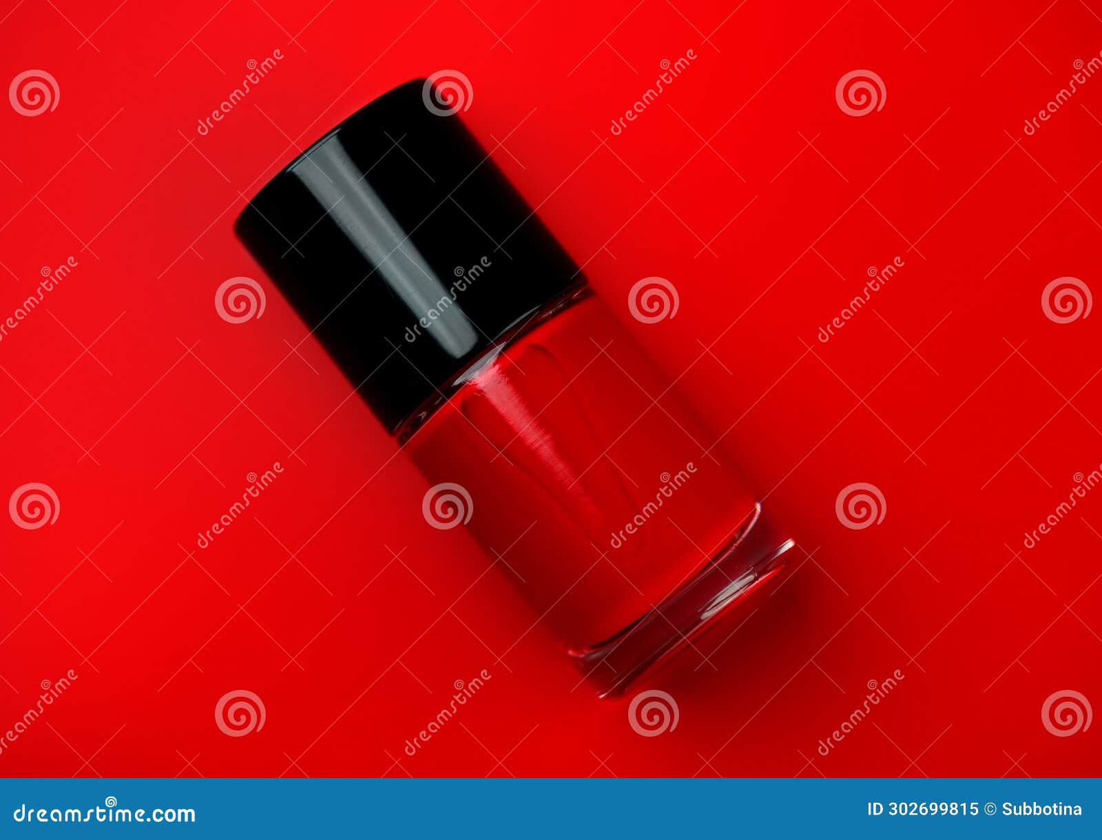 red nail polish bottle over bright red background, top view. gel nailpolish, shellac uv, bottle with brush