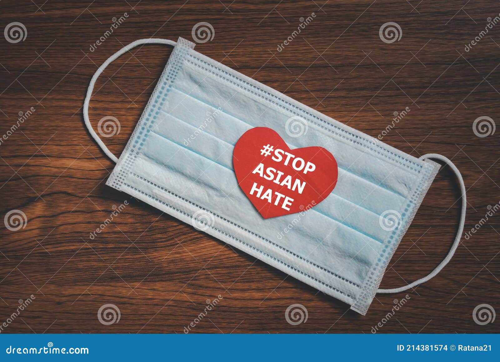 red paper heart with #stop asian hate text on surgical face mask with dark wood background