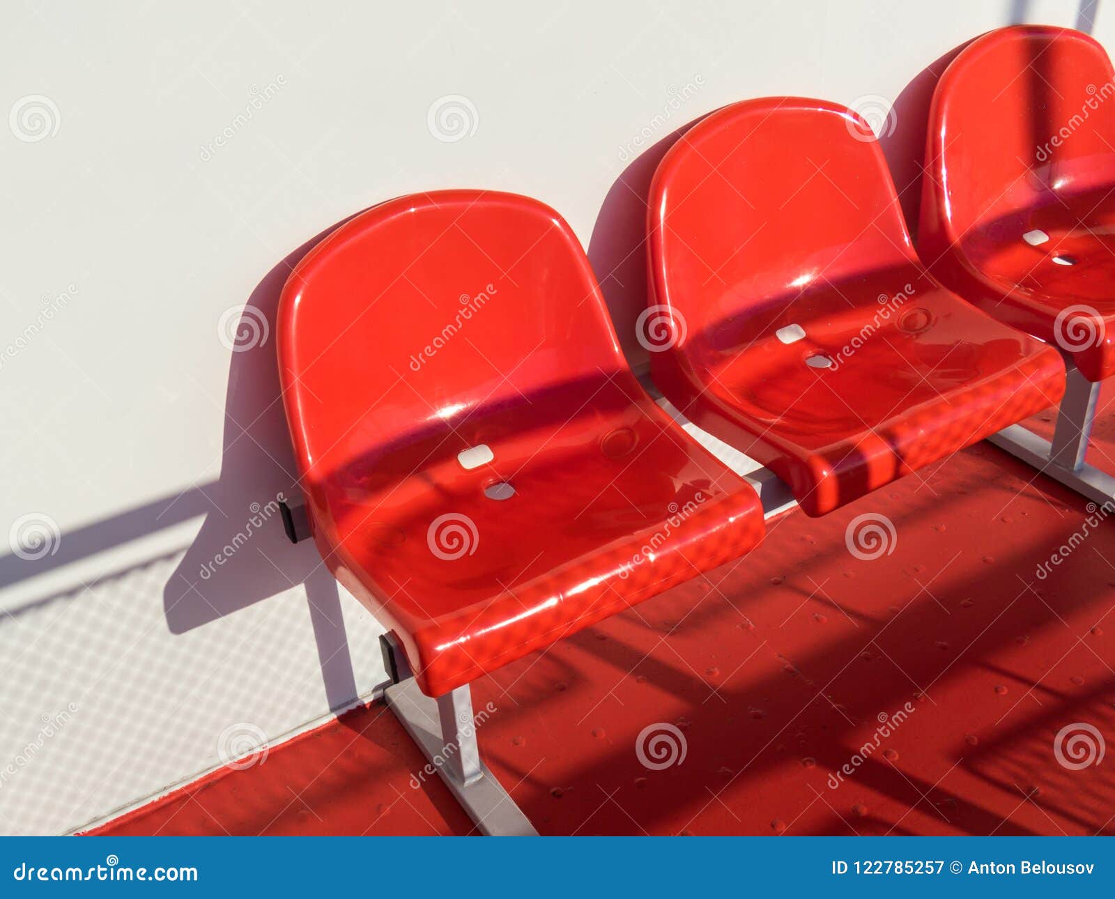 Red Plastic Chairs In Front Of A White Wall Stock Image