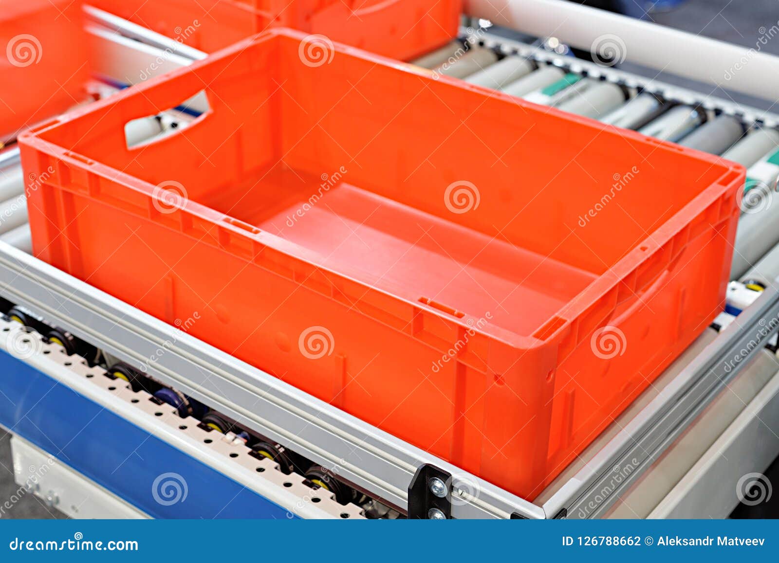 Red Plastic Containers On Roller Conveyors In An Automated