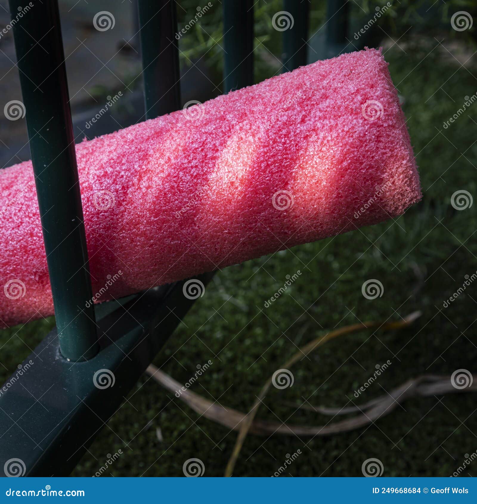 Red Pool Noodle in Pool Fence and Light in Australia Stock Photo
