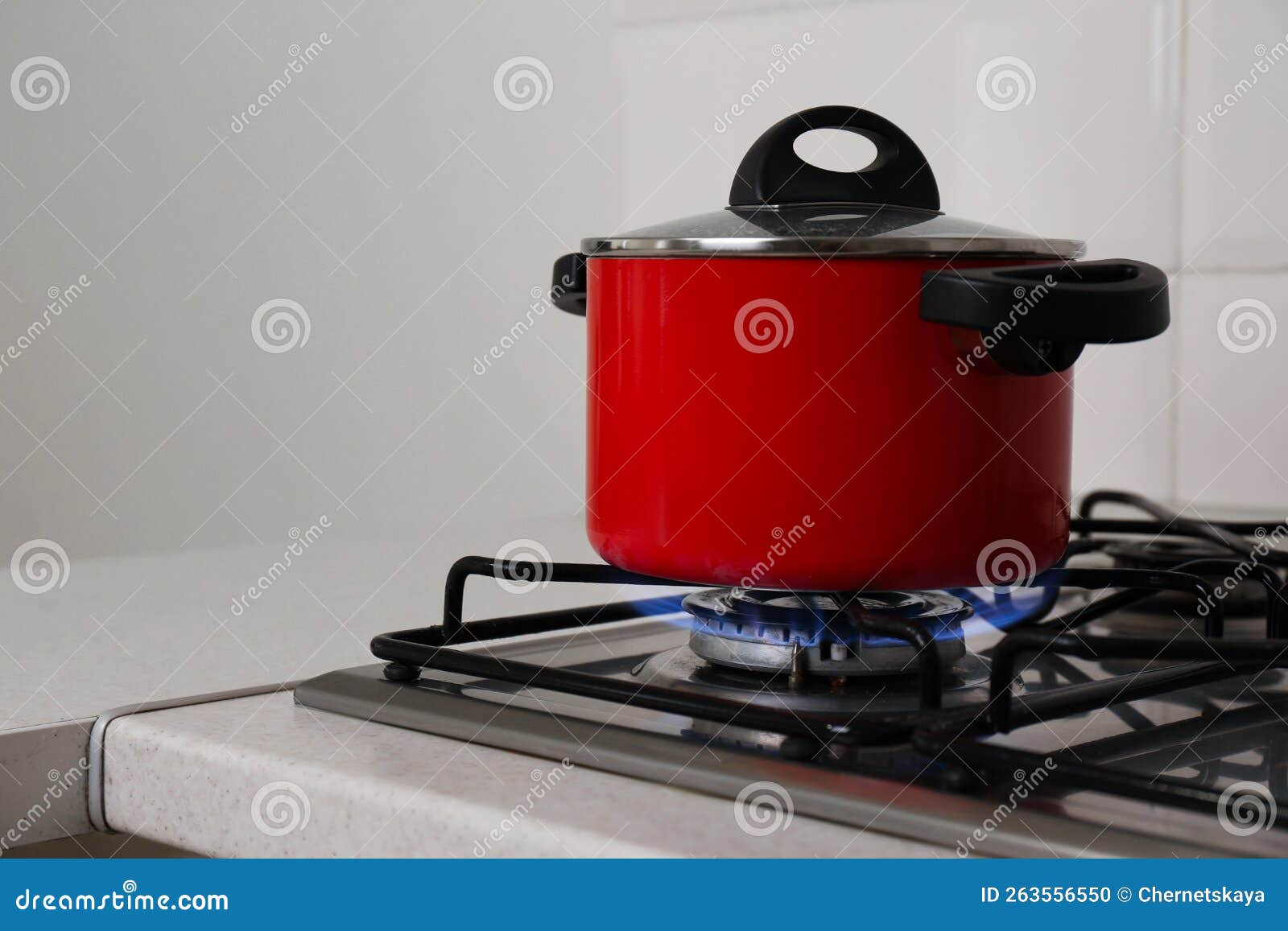 Red Pot on Stylish Kitchen Stove with Burning Gas, Space for Text Stock