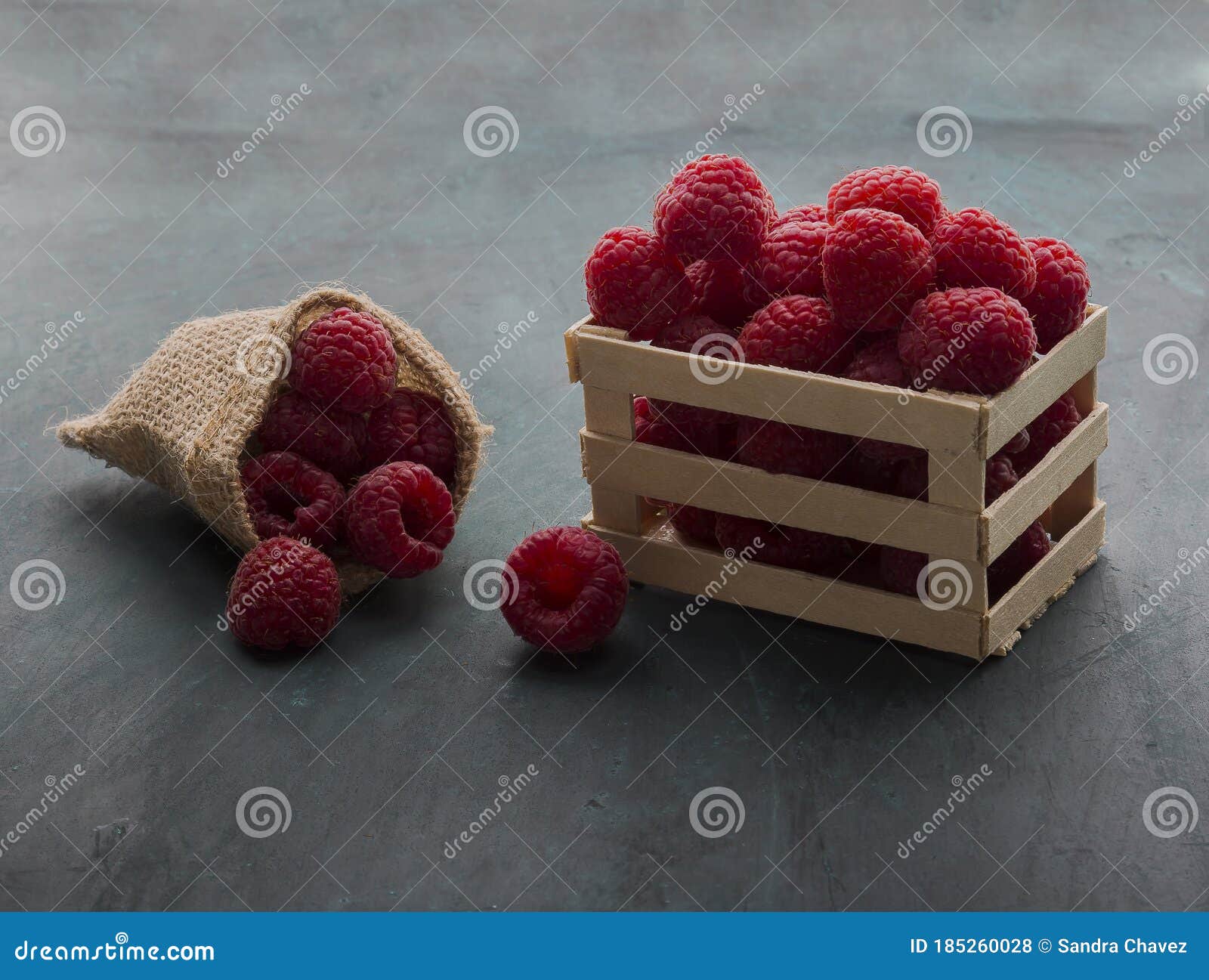 red raspberries placed on a small wooden fence and jute bag
