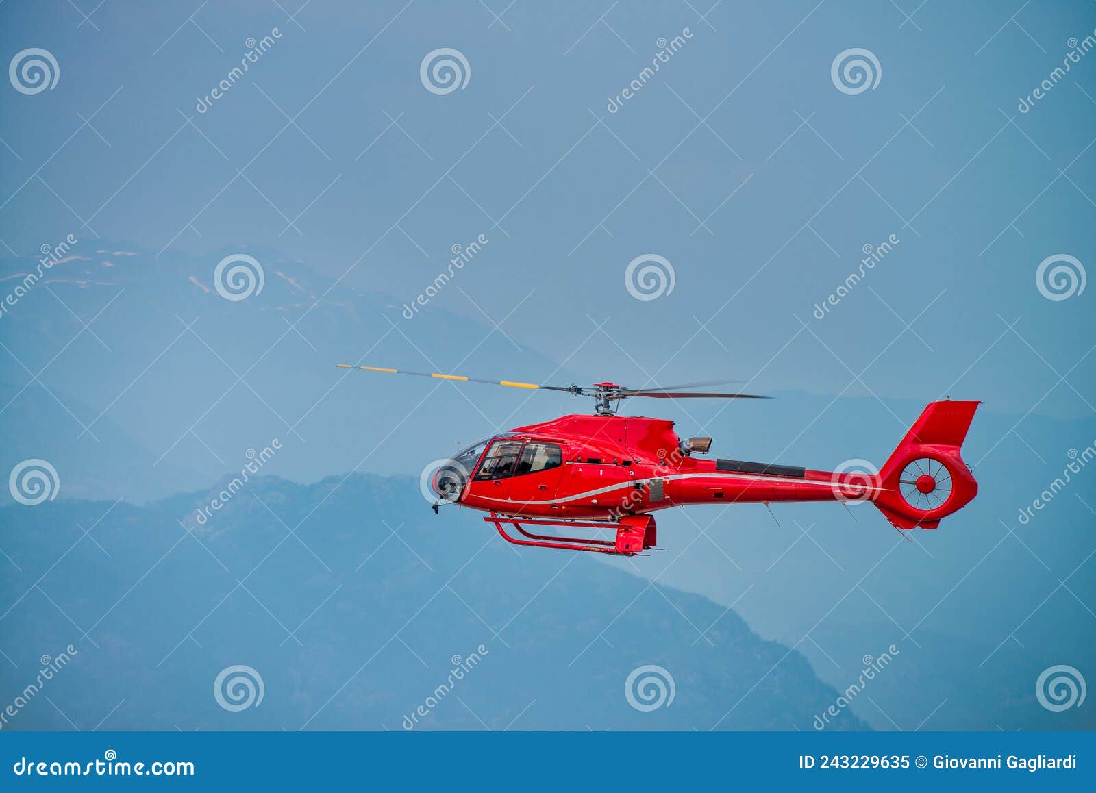 Red Rescue Helicopter Flying in a Mountain Environment Stock Image