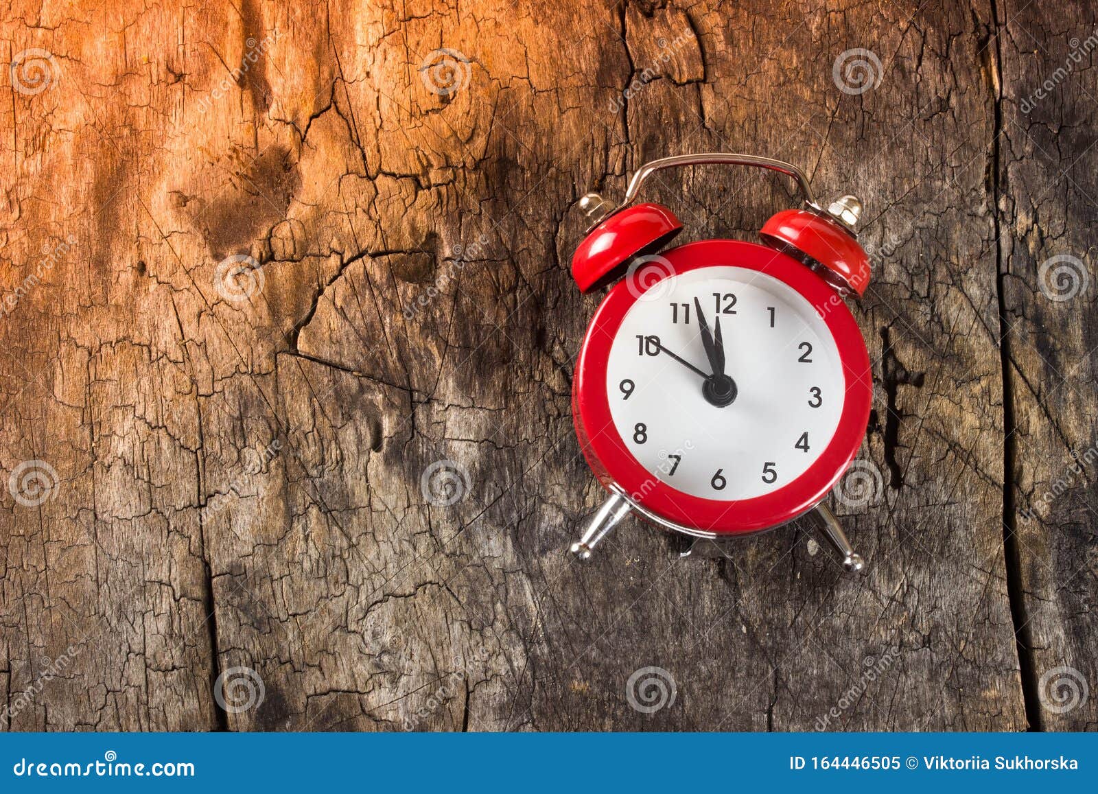 red alarm clock on wooden background. on the clock is 11 hours and 55 minutes. concept of time, christmas and new year.