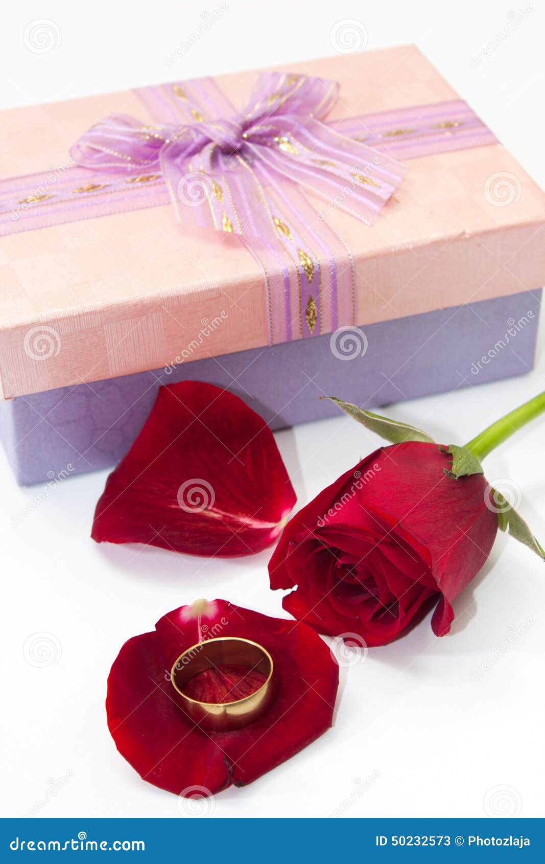 Red Rose Petals with Pink Gift Box with a Bow and Golden Ring Stock