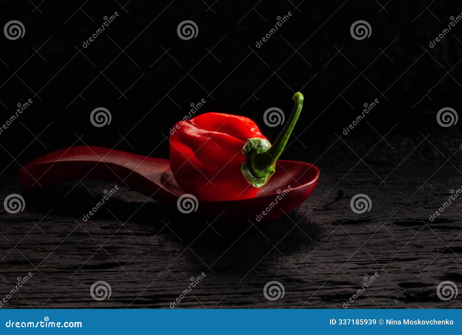 red savina habanero pepper in spoon on black wooden table.