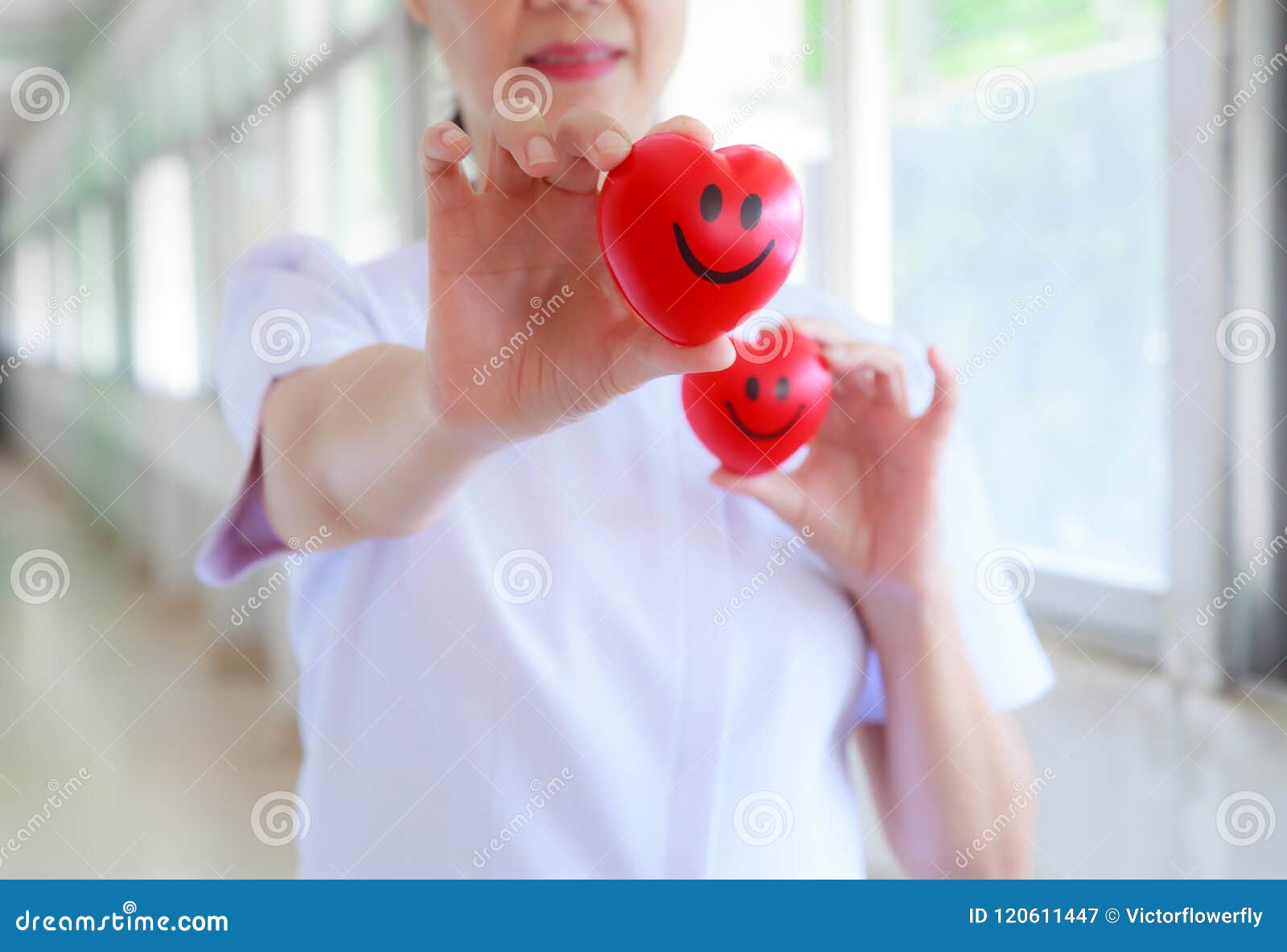 red smiling heart held by smiling female nurse`s hands in health care hospital or clinic. professional, specialist, experience