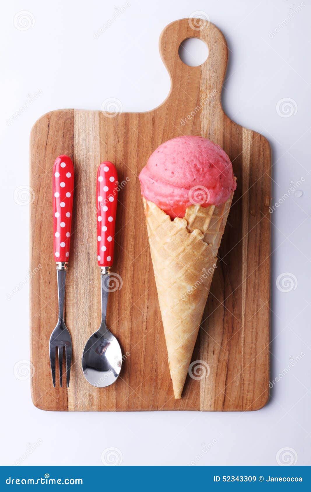 Red strawberry ice cream cone with spoon on wooden plate on white background