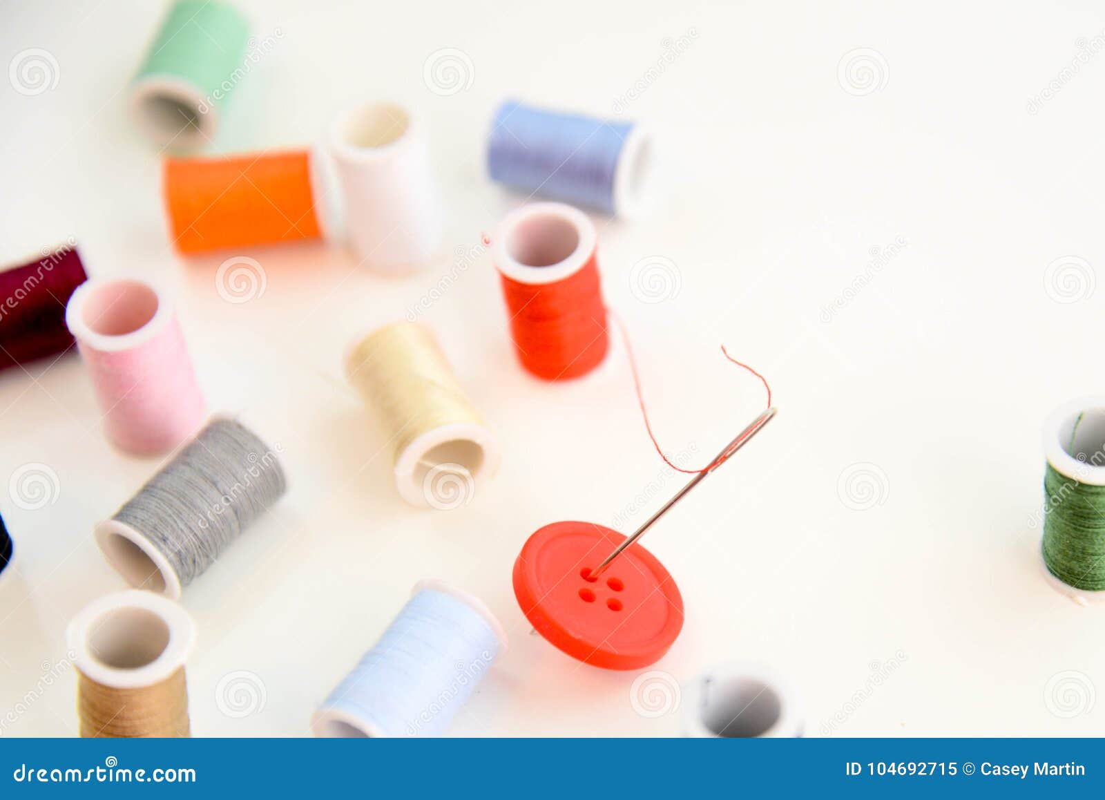 Multi Colored Thread Spools, Needle and Red Button Stock Image - Image ...