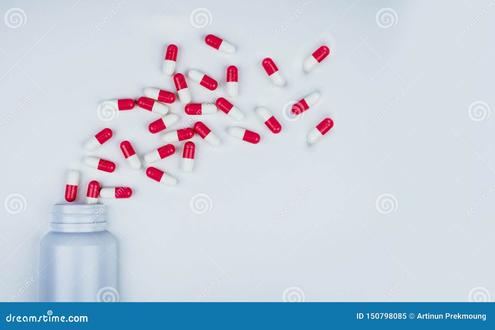 red-white antibiotic capsule pills spread out of white plastic drug bottle. antibiotic drug resistance concept. antibiotic drug