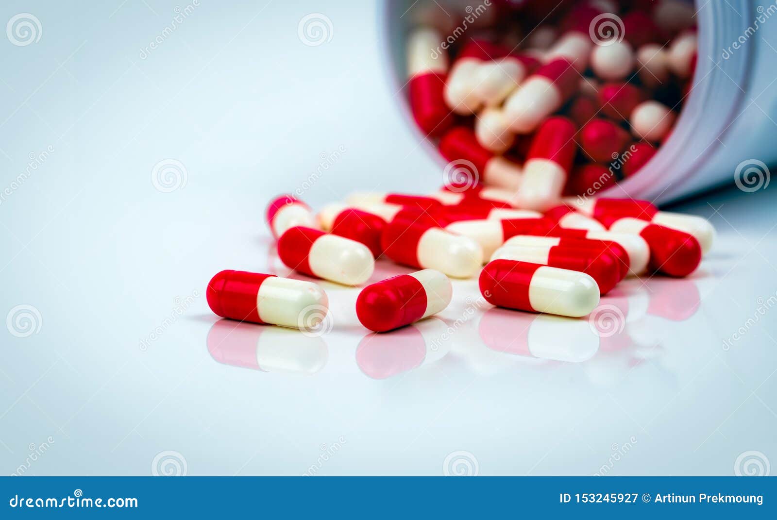 red-white capsule pills on white table on blurred background of drug bottle. antibiotics drug resistance. antimicrobial capsule