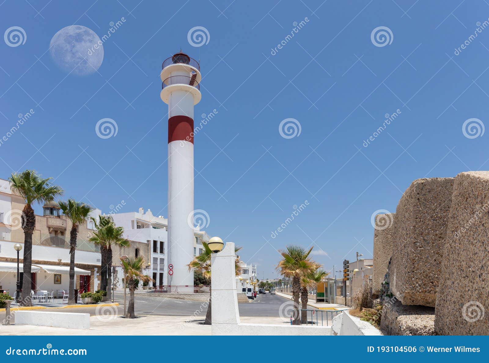 the red and white rota lighthouse with the moon in the sky.