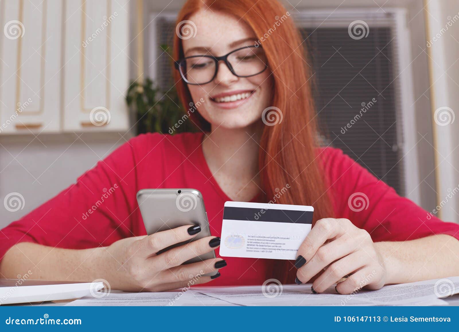 Redhaired довольно женская модель в Eyewear держит умный телефон и ...