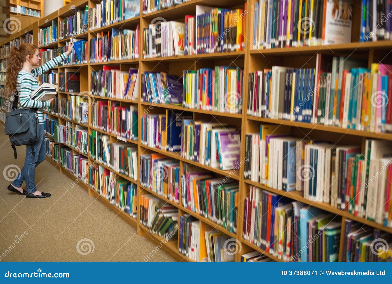 Redhead Student Taking a Book from Library Bookshelf Stock Image