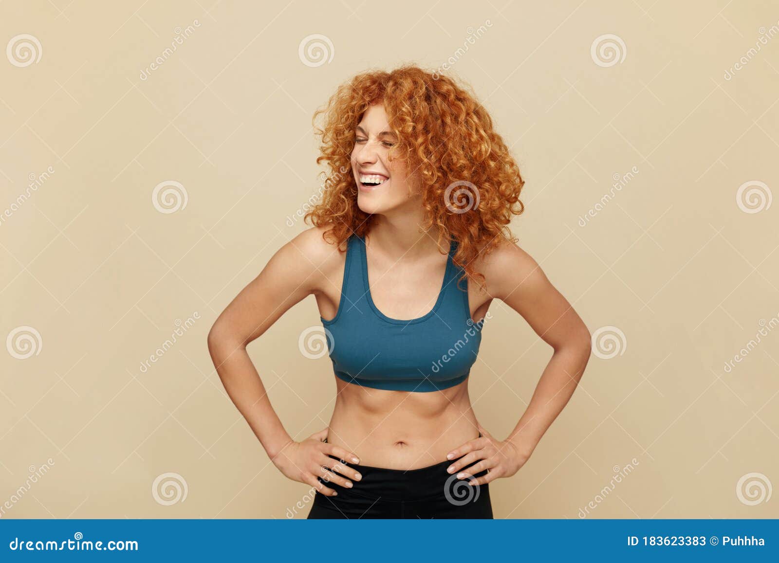 redhead woman. fit girl portrait. smiling beautiful female in sportswear keeping hands on hips.