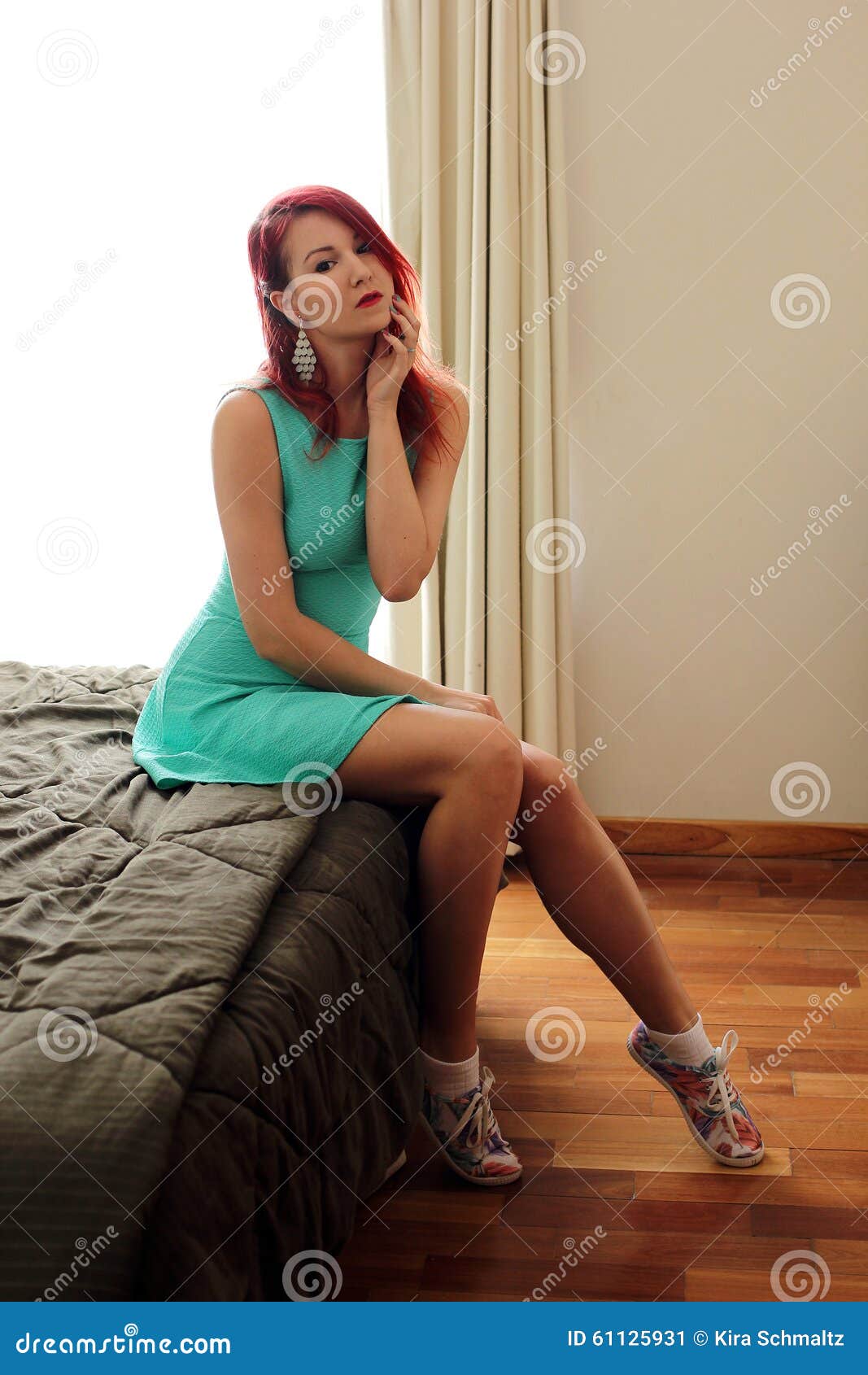 The Redhead Young Woman In Green Dress Sitting On The Bed Stock Image